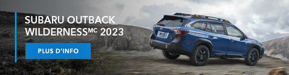 Subaru Outback Wilderness 2023 en bleu geyser, roulant sur un relief accidenté.